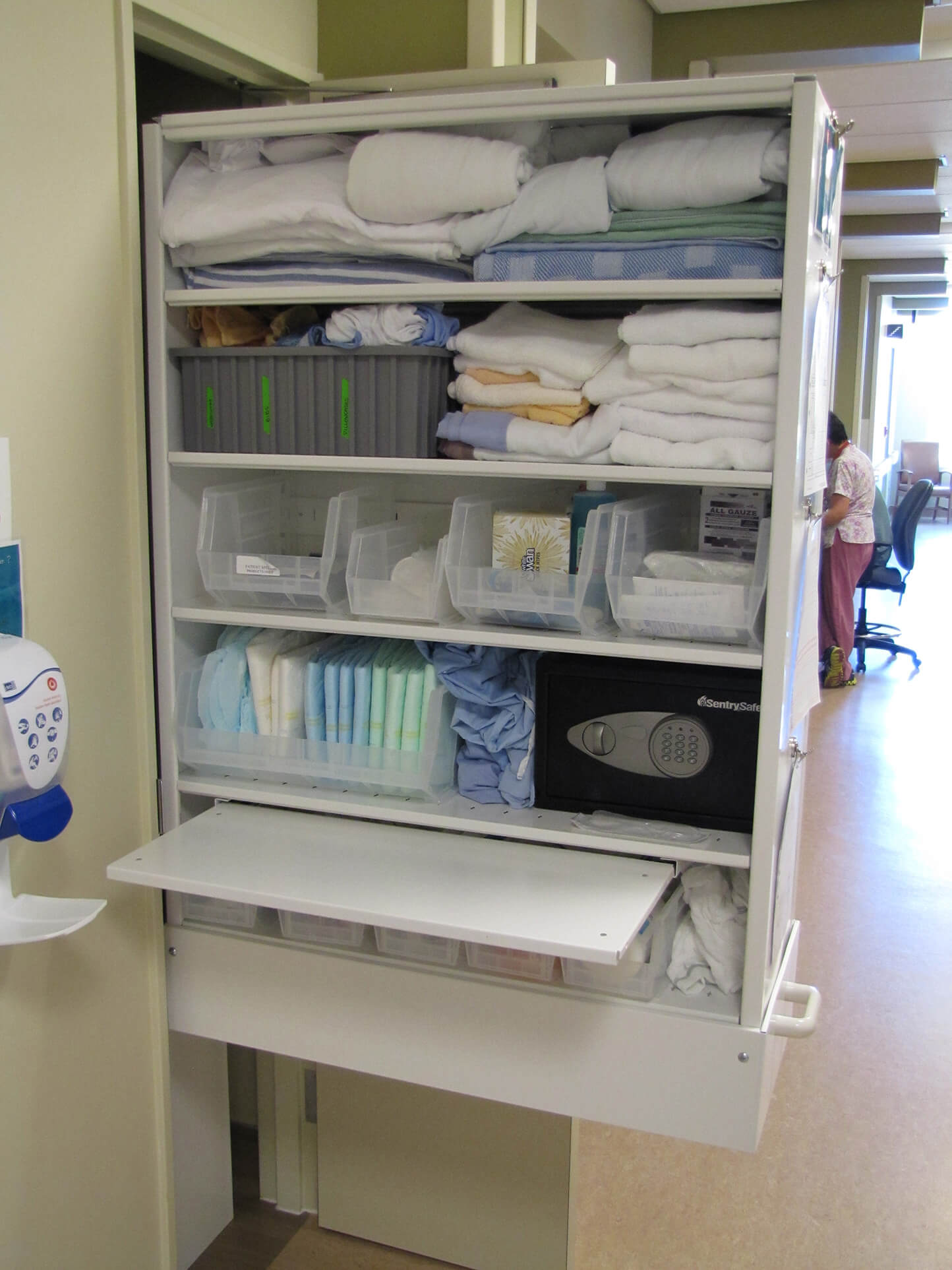 Room supplies stored on retractable shelving to replenish outside the room, yet easy access inside the room when the patient needs those supplies